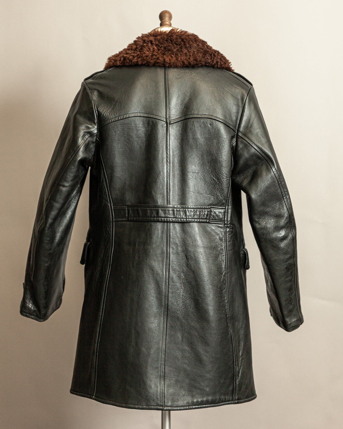 Swedish Military 1940s Black leather Trench coat with a brown wool collar on a mannequin against a beige background
