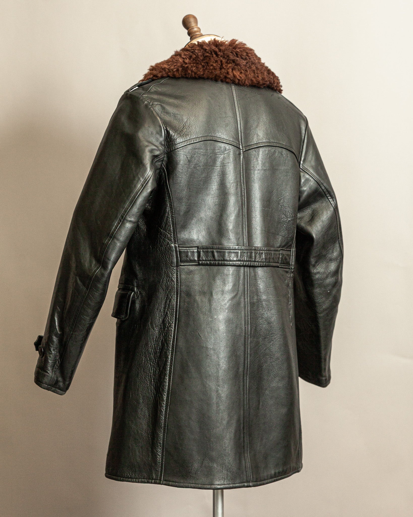 Swedish Military 1940s Black leather Trench coat with a brown wool collar on a mannequin against a beige background