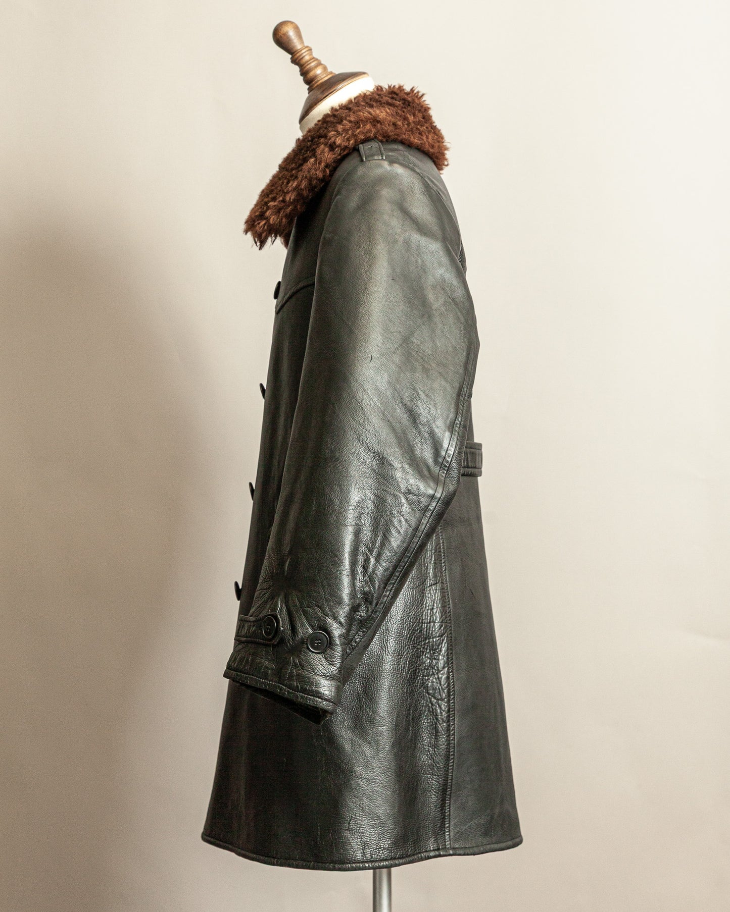 Swedish Military 1940s Black leather Trench coat with a brown wool collar on a mannequin against a beige background