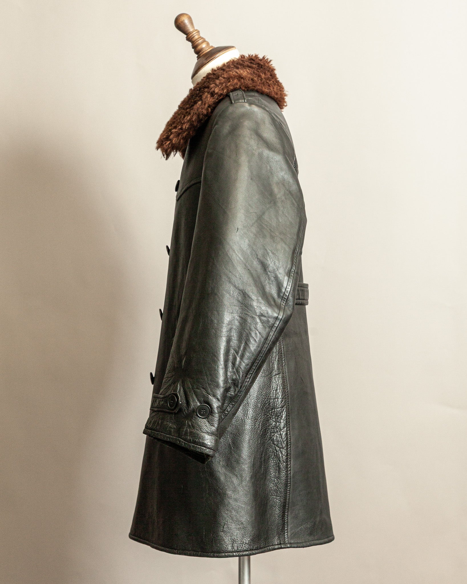 Swedish Military 1940s Black leather Trench coat with a brown wool collar on a mannequin against a beige background