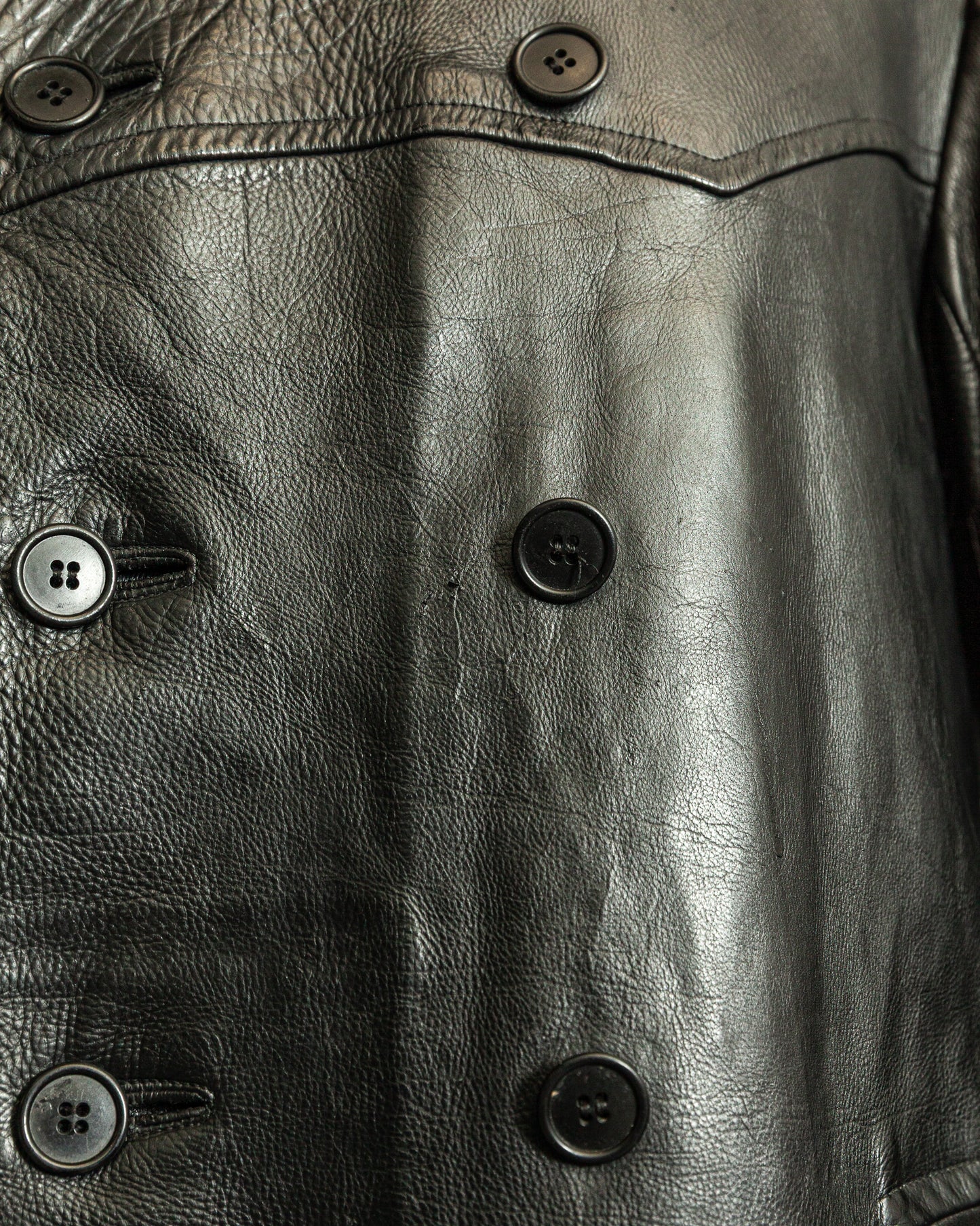 Close-up of a black leather jacket with button details