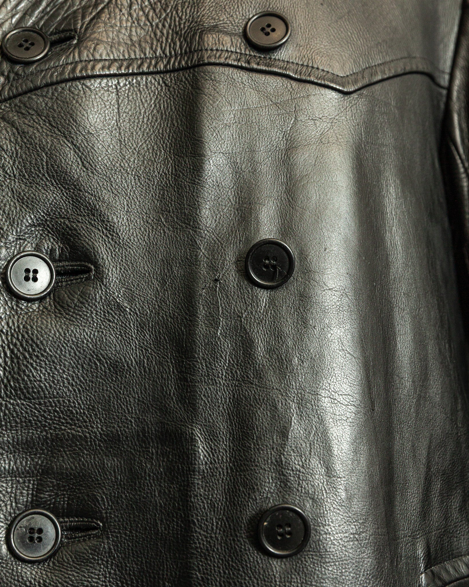 Close-up of a black leather jacket with button details
