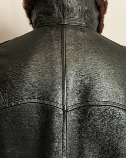 Close-up of a black leather jacket with fur lining on a neutral background