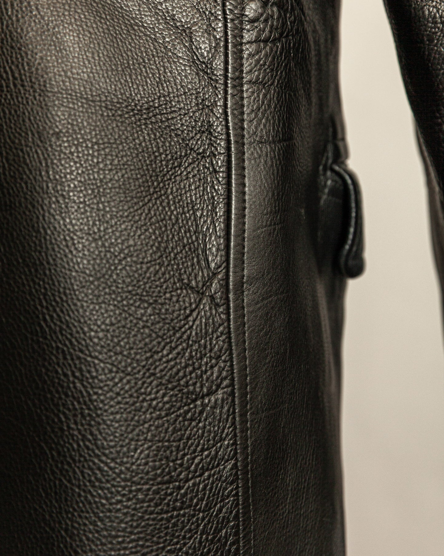 Close-up of a black leather jacket with visible stitching on a neutral background