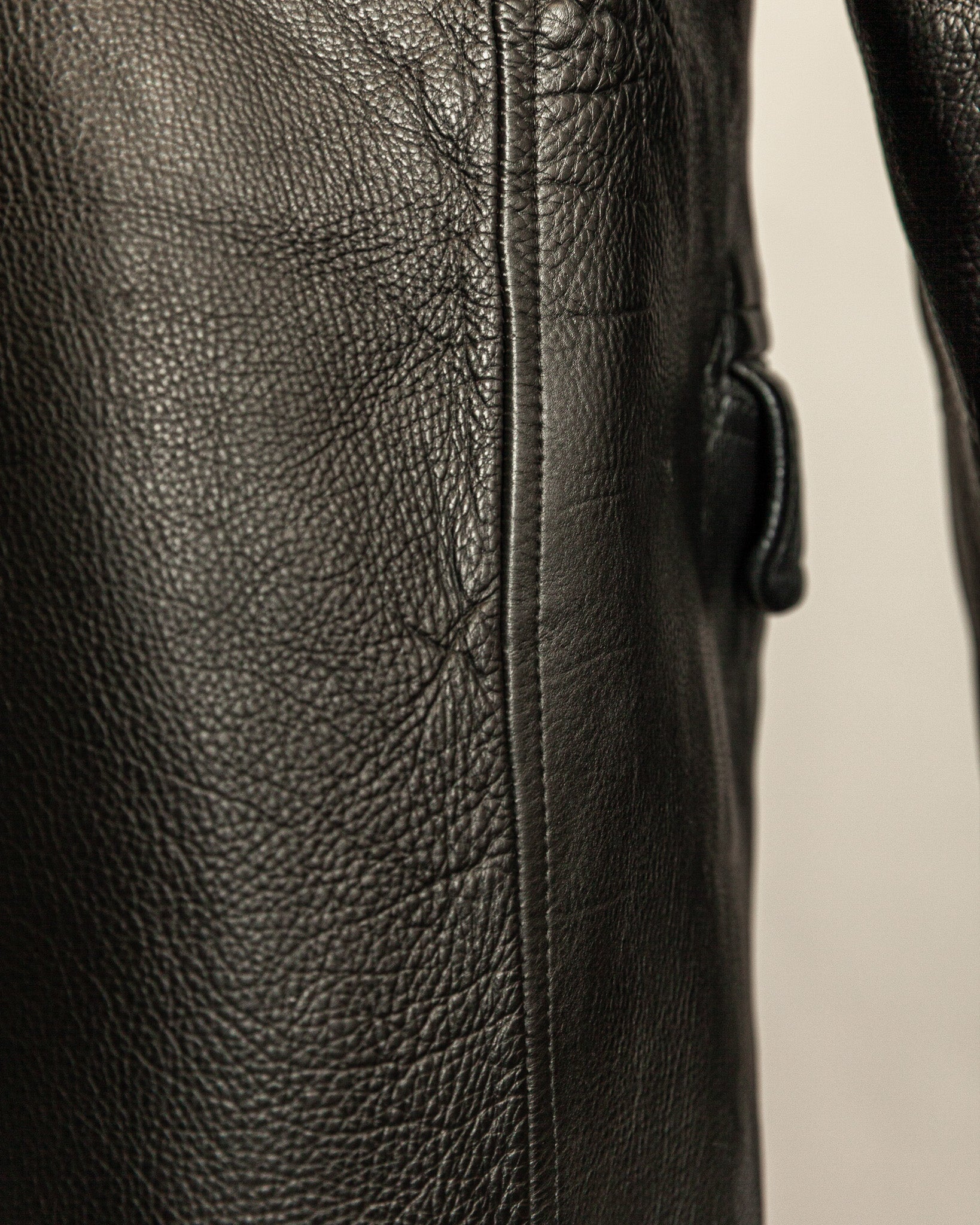 Close-up of a black leather jacket with visible stitching on a neutral background