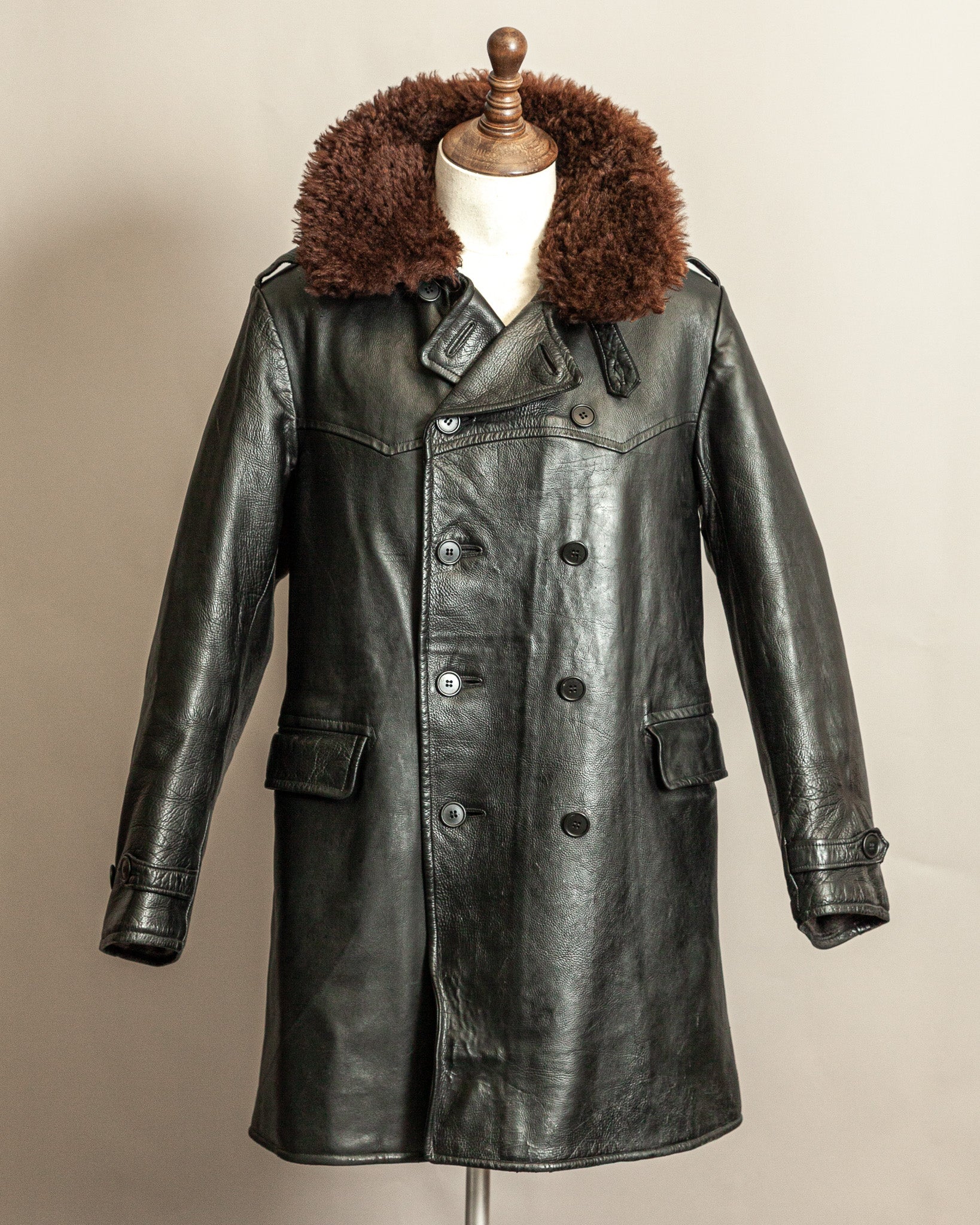 Vintage Swedish WW2 1940s Black Goatskin leather long army trench coat with real wool collar on a mannequin against a beige background