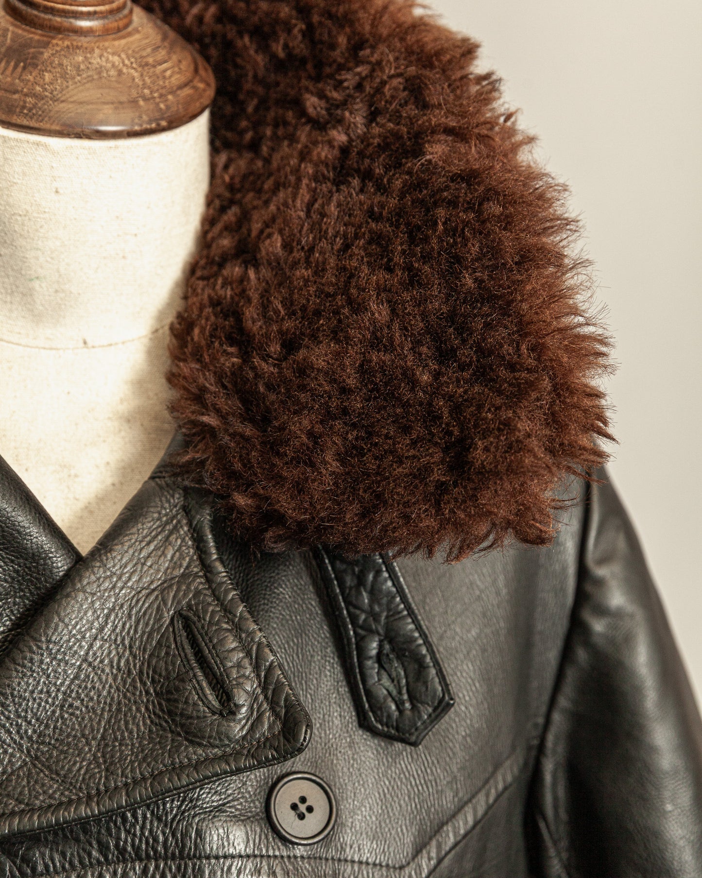 Black leather jacket with a brown fur collar on a mannequin.