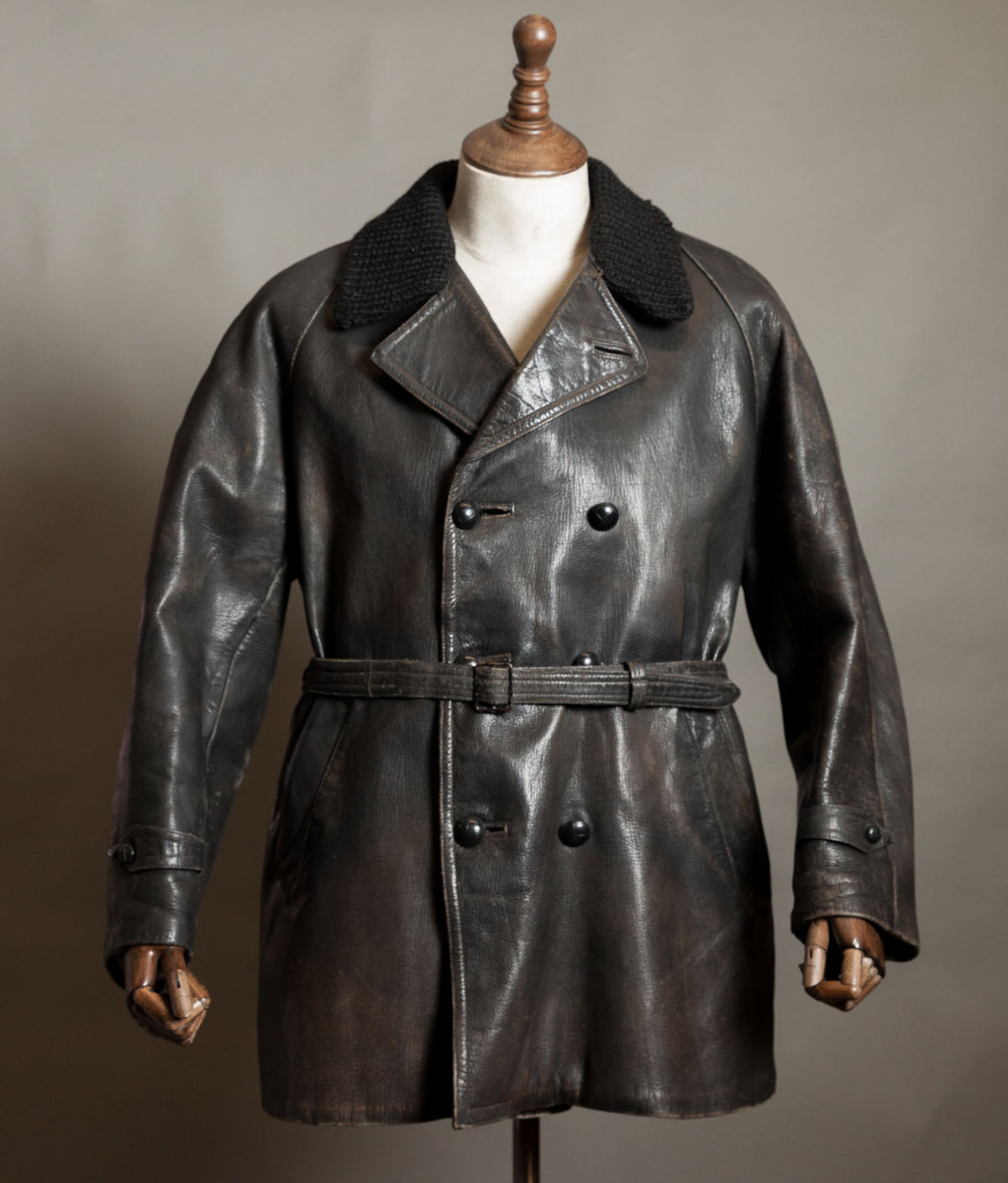 Vintage Italian double-breasted goatskin police motoring coat with knitted wool collar and belt, displayed on a wooden mannequin