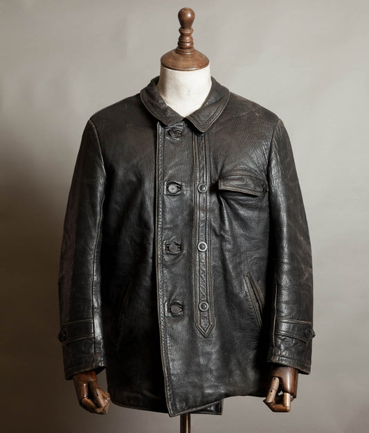 Vintage 1970s French Le Corbusier black leather work jacket with pointed double placket and collar, displayed on a wooden mannequin