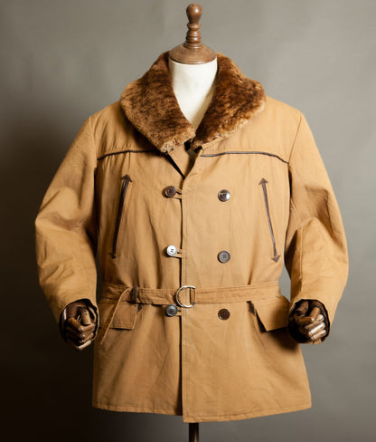 Vintage 1950s French canadienne coat in tan canvas with a brown mouton shawl collar, double-breasted buttons, leather trim and belted waist