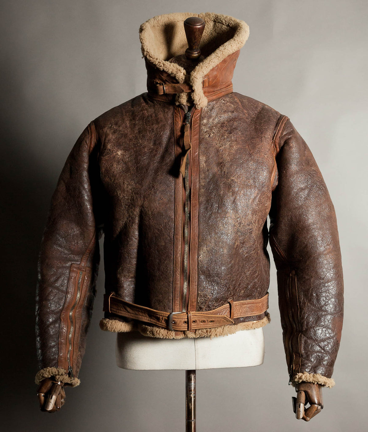 Original 1939 RAF Irvin sheepskin flying jacket in dark brown leather, collar turned up and buckled, belted waist, on a vintage tailor’s dummy